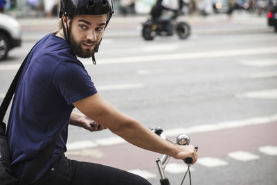 Man wearing helmet cycling on city street