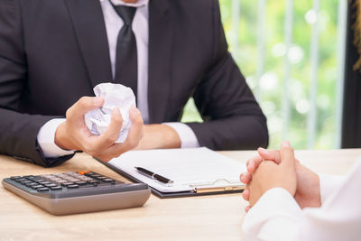 Midsection of man holding hands on table