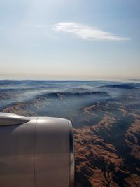 Cropped image of airplane engine flying over mountains against sky