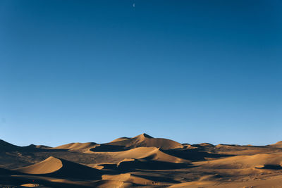 Scenic view of desert against clear blue sky