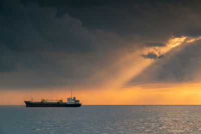 Ship sailing on sea against sky during sunset