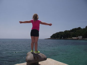 Rear view of man standing by sea against sky