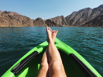 Low section of woman relaxing in boat on lake