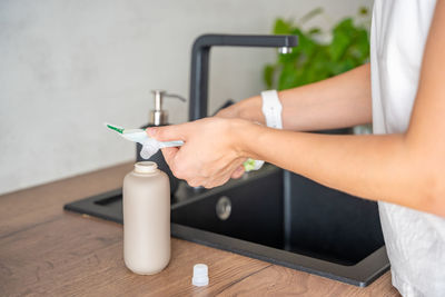 Midsection of woman holding bottle on table