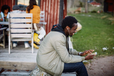 Young man using mobile phone while sitting on bench