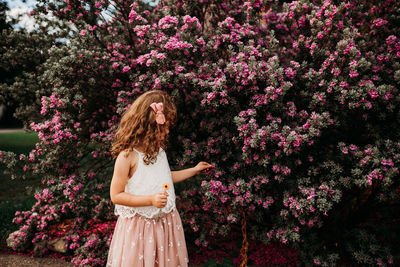 Young girl surrounded by purple flowers outside on summer day