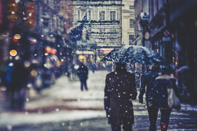 Rear view of people walking on wet road in city