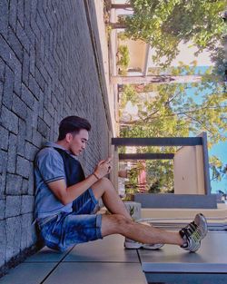 Young man sitting against wall