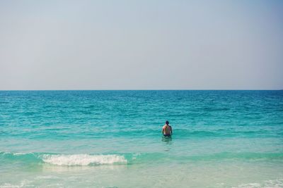 Rear view of man standing in sea against clear sky