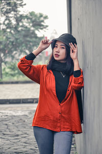 Young woman standing against wall