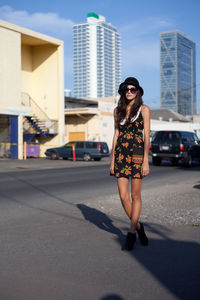 Young woman on sunglasses in city against sky