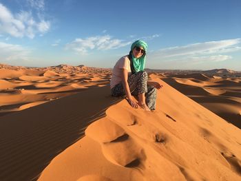 Woman standing on sand dune in desert against sky