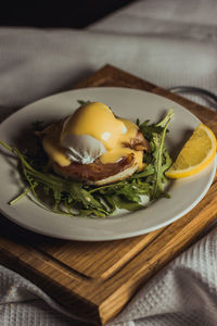 Eggs benedict and poached hollandaise sauce with arugula and lemon. delicious food for breakfast. 