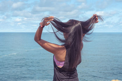 Midsection of woman against sea with sky in background