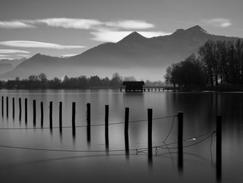 Wooden posts in lake against sky