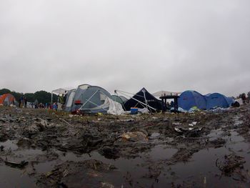 Muddy field by tents at campsite against clear sky