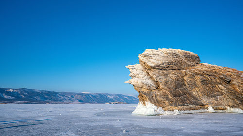 Rock formation against clear blue sky during winter