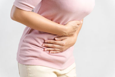 Midsection of woman wearing hat against white background