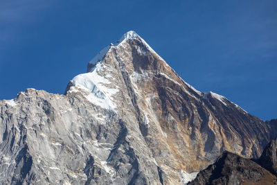 Low angle view of snowcapped mountain against blue sky