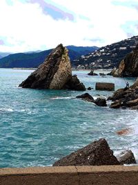 Rocks on shore by sea against sky