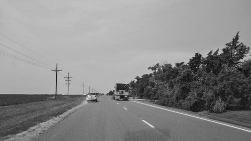 Road by trees against clear sky