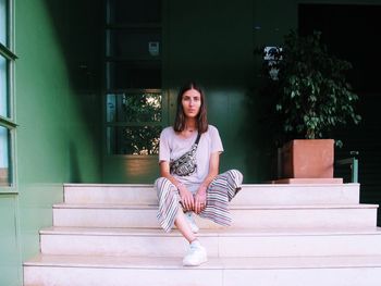 Portrait of young woman waiting while sitting on staircase