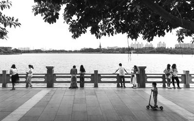 People standing by sea against clear sky