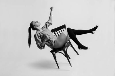 Fashionable young woman looking up while sitting on chair