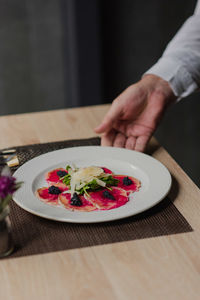 Cropped hand of person having food in plate on table