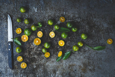 Directly above shot of kumquats with knife on kitchen counter