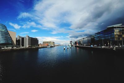 City at waterfront against cloudy sky