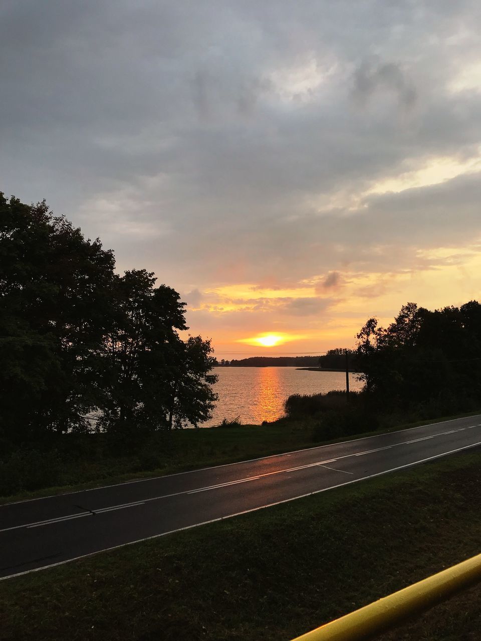 ROAD BY TREES AGAINST SKY AT SUNSET