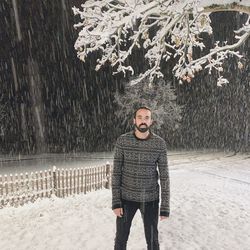 Portrait of young man standing against trees in winter