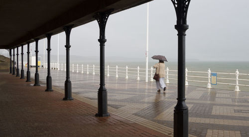 Man standing by railing against sea