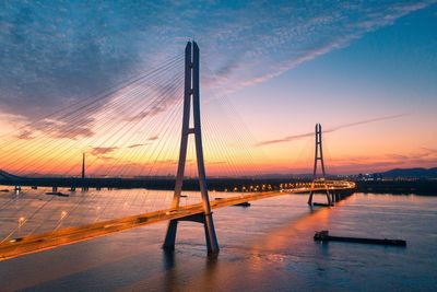 View of suspension bridge over sea during sunset