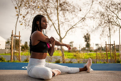 Full length of young woman sitting on wall