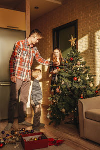 Rear view of woman standing by christmas tree