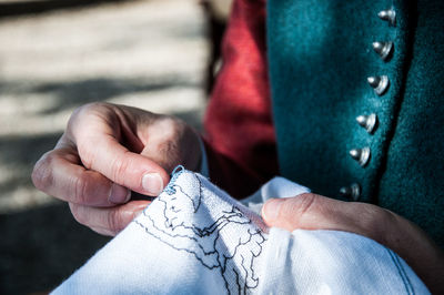Midsection of person making embroidery on fabric