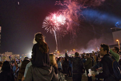 People looking at firework display at night