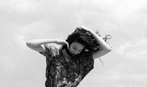 Woman with tousled hair standing against sky