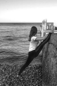 Rear view of woman on sea shore against sky