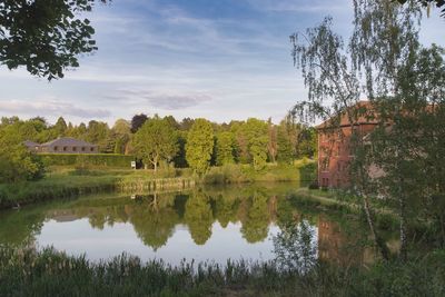 Scenic view of lake by trees and building against sky