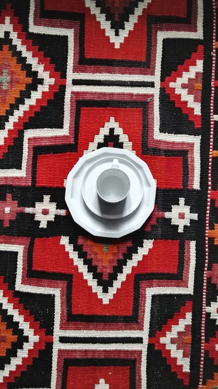 High angle view of empty cup and saucer on tablecloth