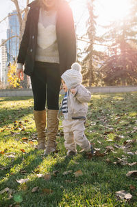 Mother with boy walking at park on sunny day