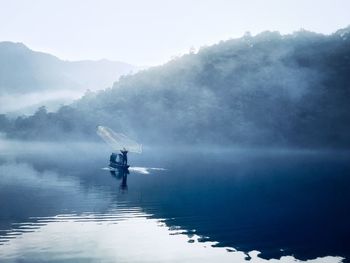 Fisherman throwing net in lake