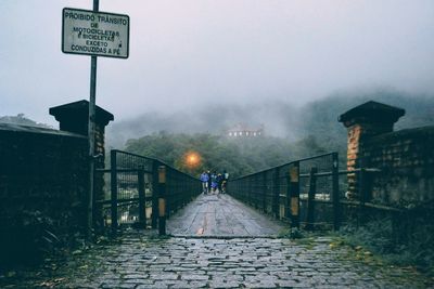 Road by bridge against sky during foggy weather