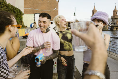 Happy non-binary friends having fun while partying on promenade in city