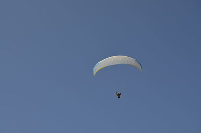 Low angle view of person paragliding against clear sky