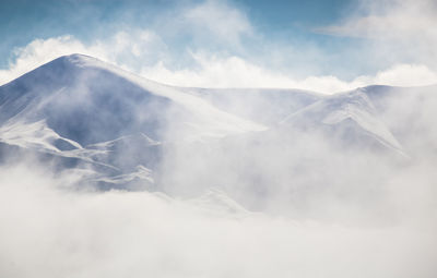 Low angle view of mountain against misty sky