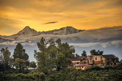 Scenic view of mountains and buildings against sky during sunset